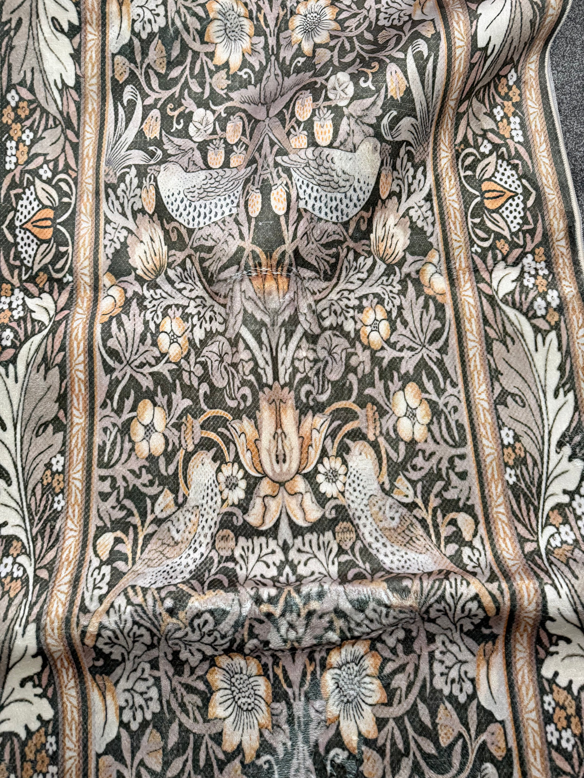 Dark botanical rug with pale birds, flowers, leaves and an ornamental border