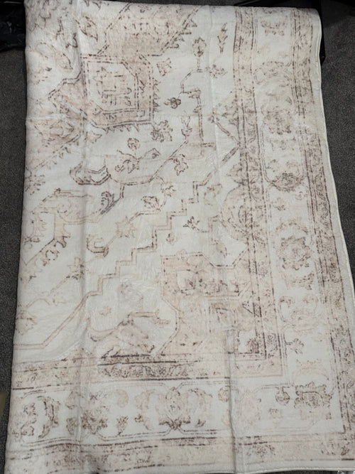 Cream and taupe rug with a faded traditional border pattern