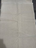 Close-up of a neutral grey-beige textured rug with bound edges