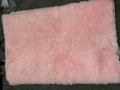 Pink shaggy rectangular rug photographed on a dark floor