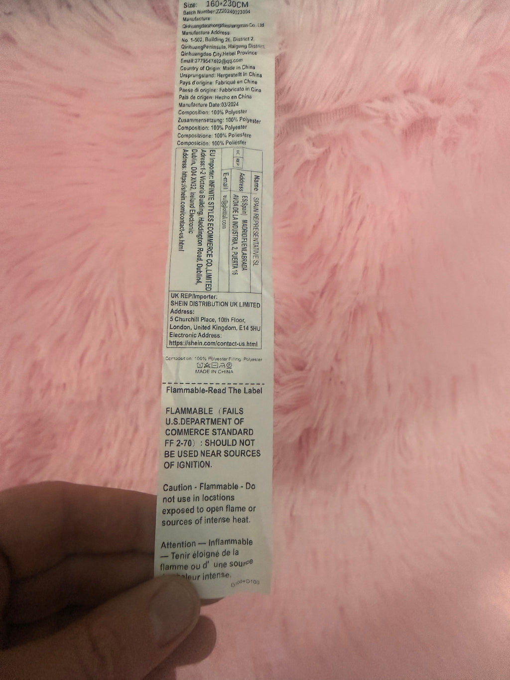 Pink rug label showing 160 x 230 cm, polyester composition and flammability warning