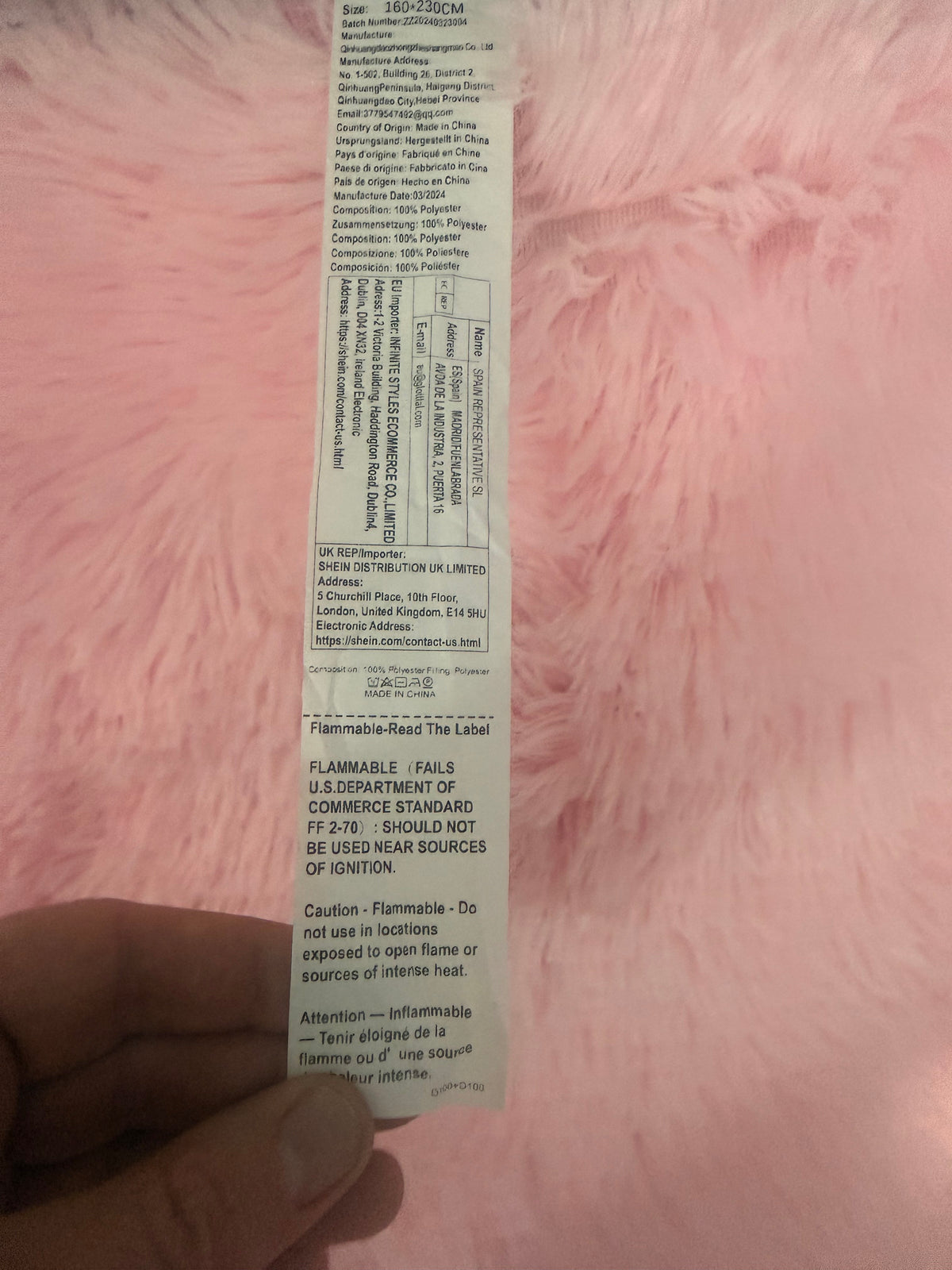 Pink rug label showing 160 x 230 cm, polyester composition and flammability warning