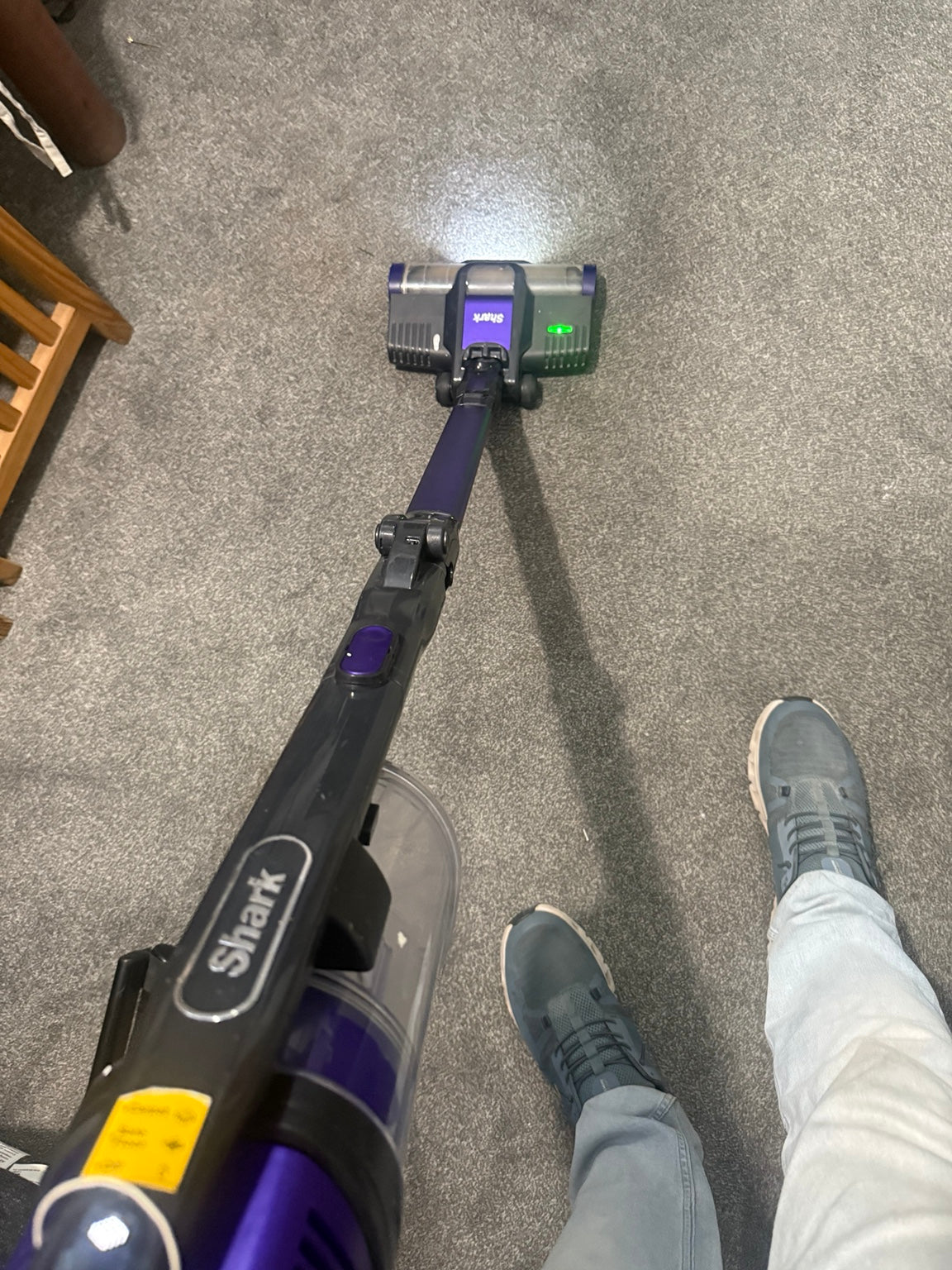 Actual purple Shark cordless vacuum cleaner on carpet with its floor-head indicator illuminated