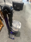 Actual pre-owned purple and dark grey Shark cordless vacuum cleaner with wand folded